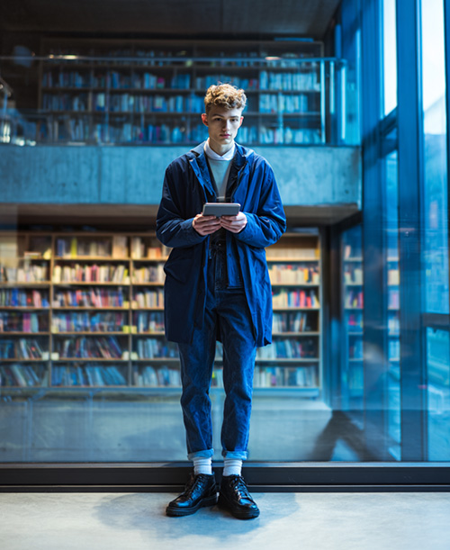 A man in a library using his Apple iPad Mini 6